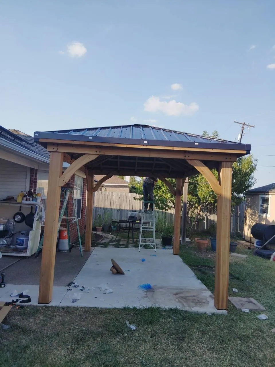 Cedar pavilion with a metal roof built over a new concrete patio slab