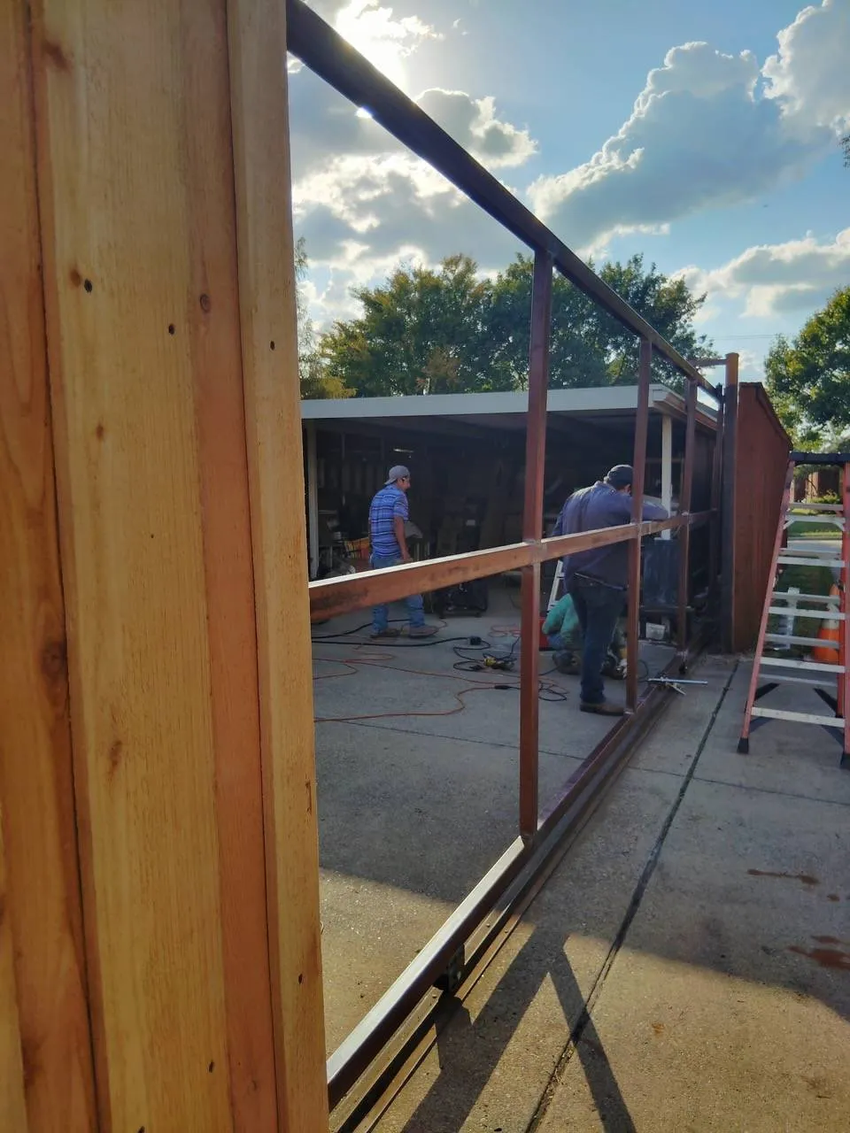 Crew setting a steel frame along a concrete slab for an outdoor structure